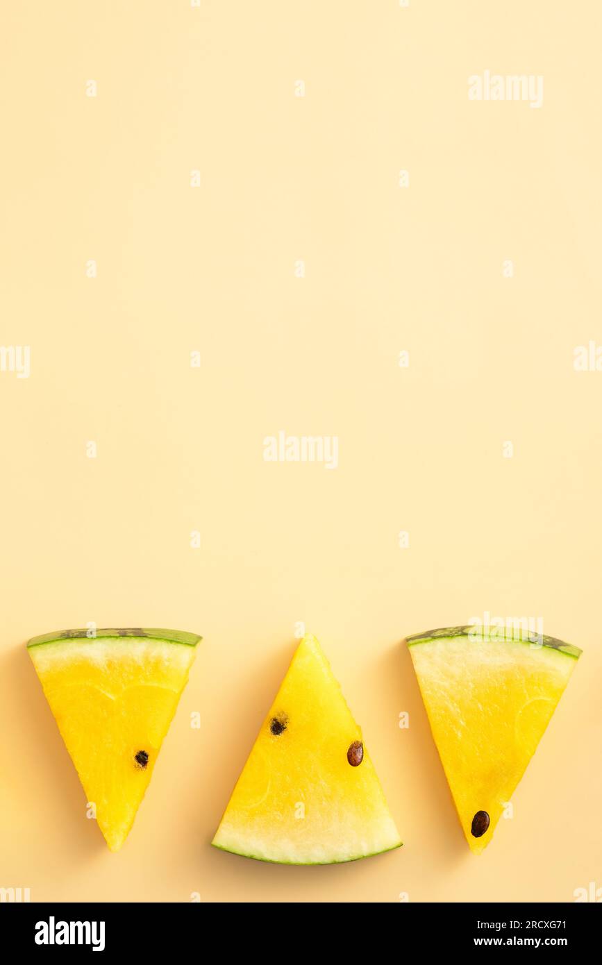 Sliced yellow golden watermelon pattern flat lay on pastel yellow table background. Stock Photo
