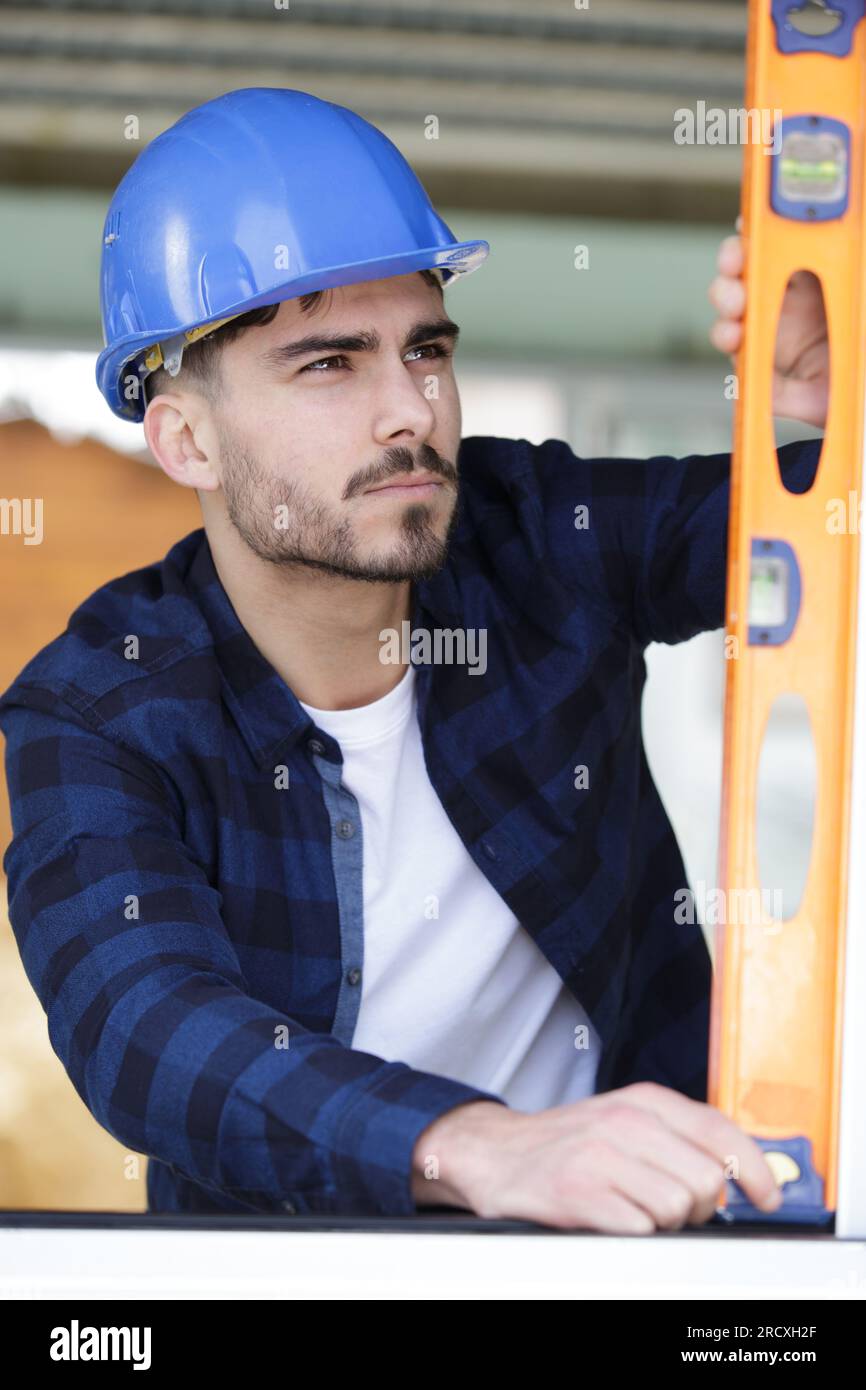 focused young builder using spirit level Stock Photo