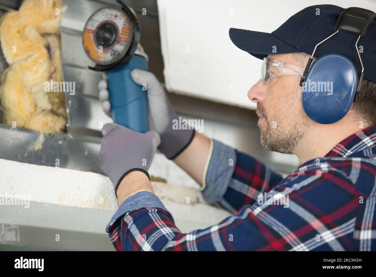 worker using angle grinder to cut through metal framework Stock Photo