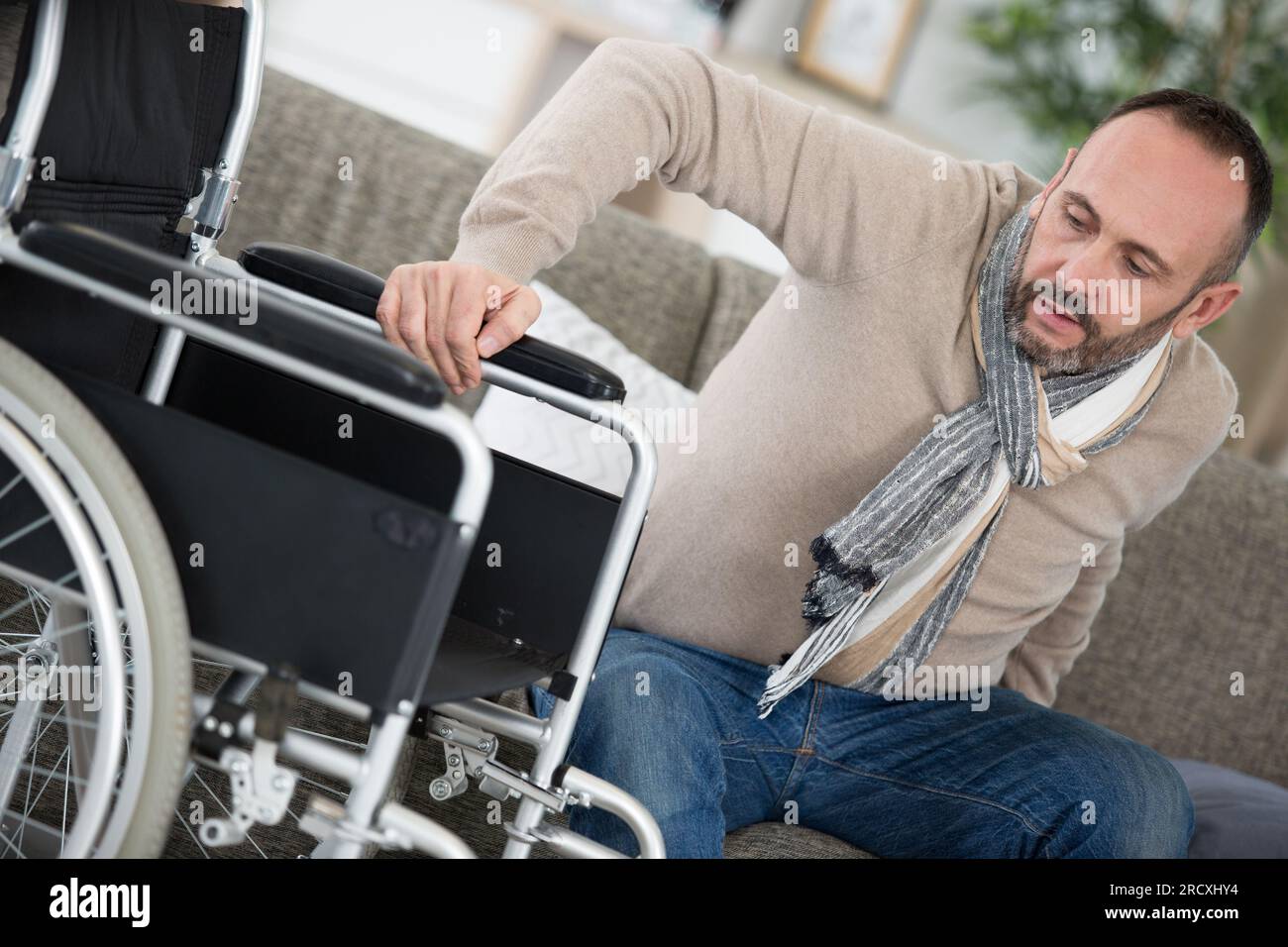 disabled man moving himself into a wheelchair Stock Photo Alamy