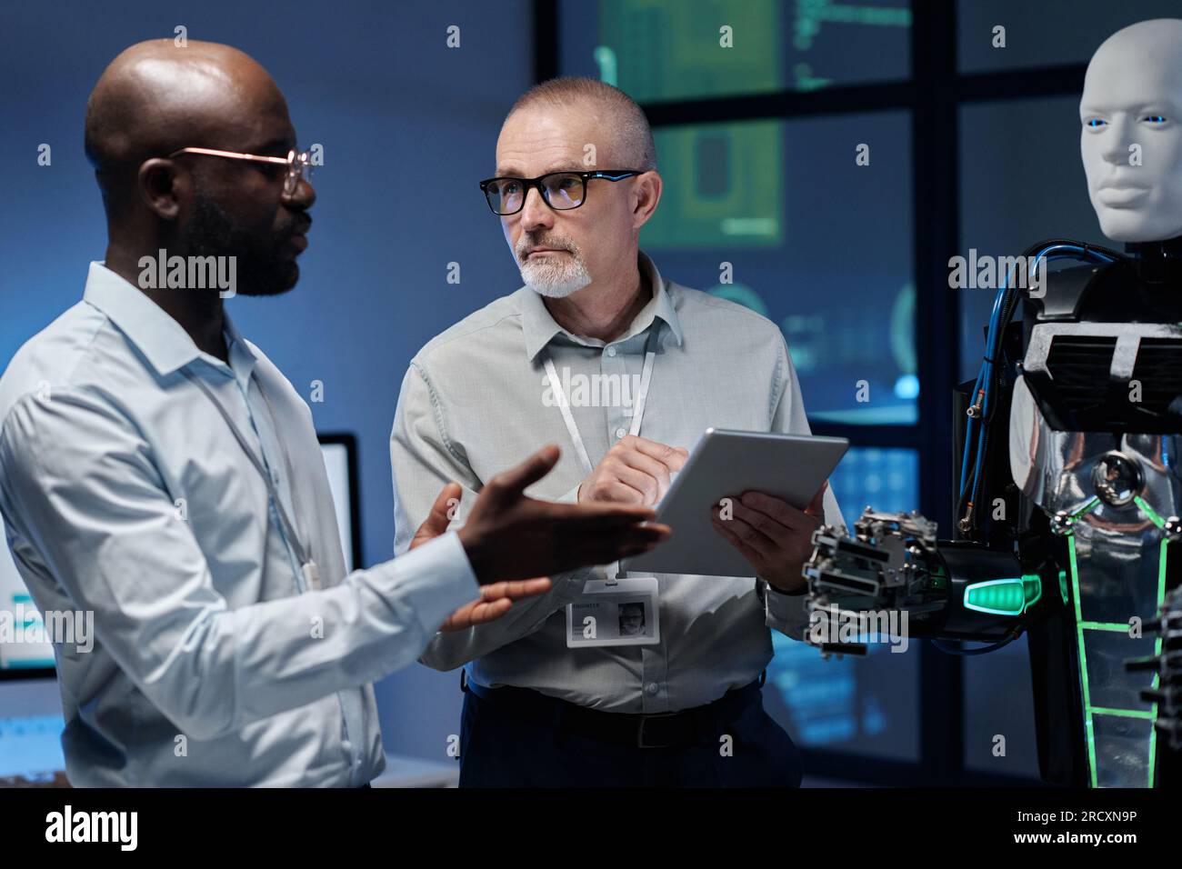 Multiethnic engineers using digital tablet to work with artificial intelligence in team in office Stock Photo
