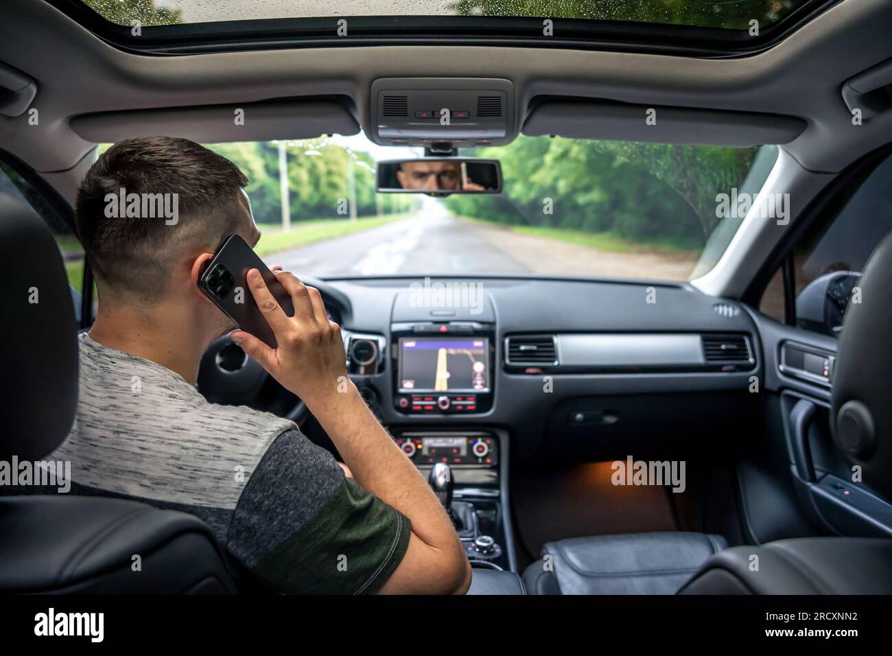 Businessman talking on cell phone while driving. Stock Photo