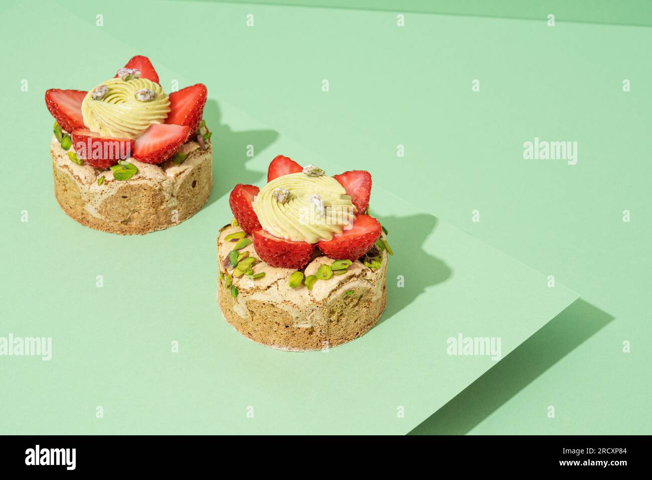 Two delectable desserts topped with fresh strawberries sitting on a plain white background Stock Photo
