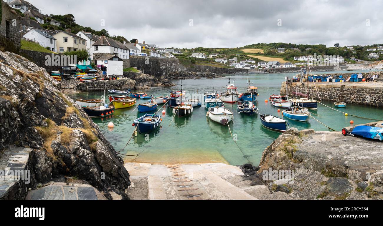 COVERACK, CORNWALL, UK - JUNE 27, 2023.   Landscape view of traditional Cornish fishing boats moored in the tidal harbour of the picturesque fishing v Stock Photo