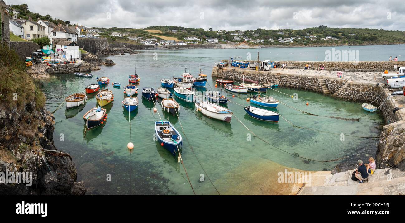 COVERACK, CORNWALL, UK - JUNE 27, 2023.   Landscape view of traditional Cornish fishing boats moored in the tidal harbour of the quaint fishing villag Stock Photo