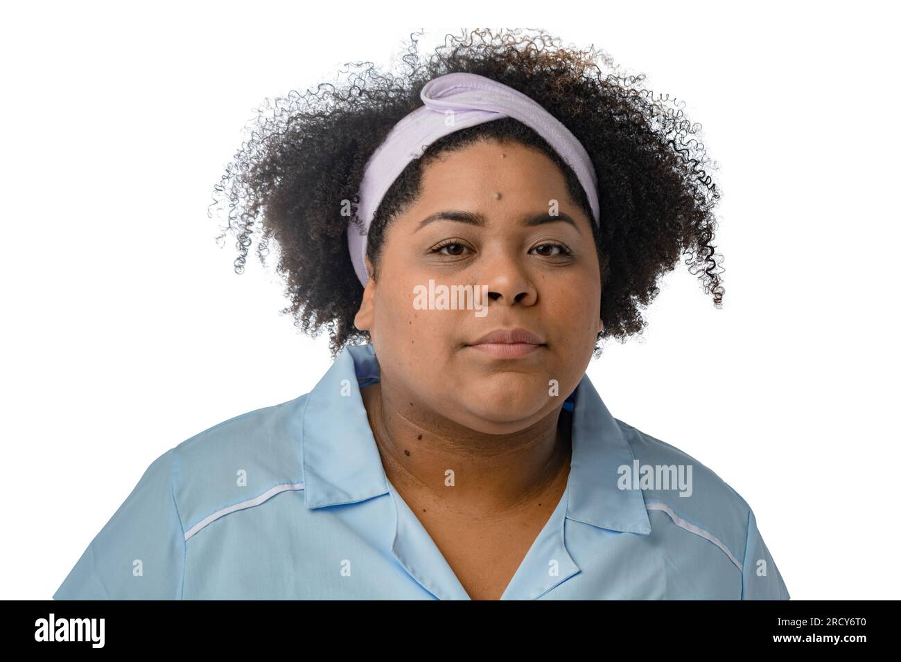 portrait of brunette woman with a head band for facial cleansing wear blue uniform and looking at the camera seriously. white background - copy space. Stock Photo