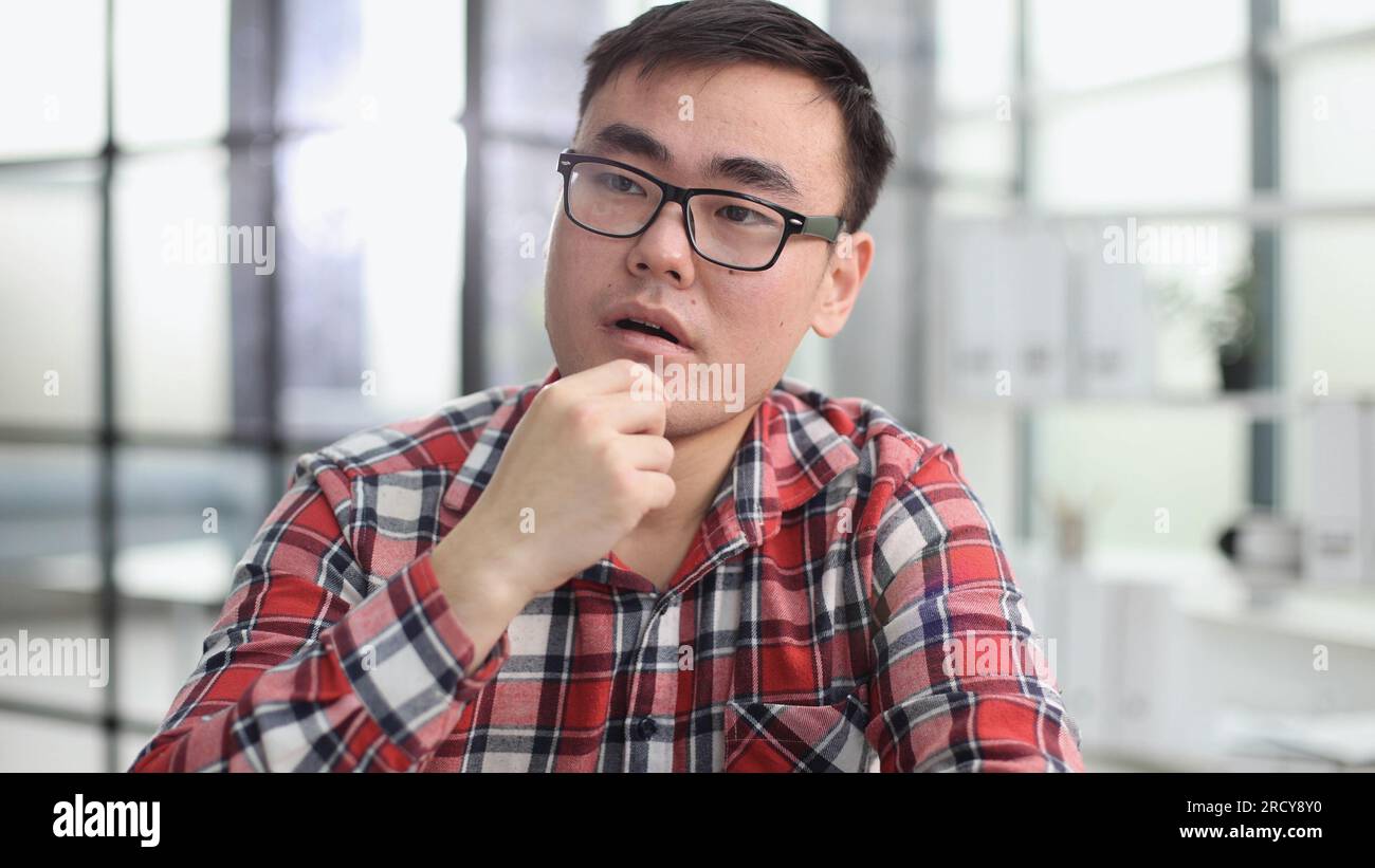 a young investor in casual clothes sits at a table and thinks about profit Stock Photo