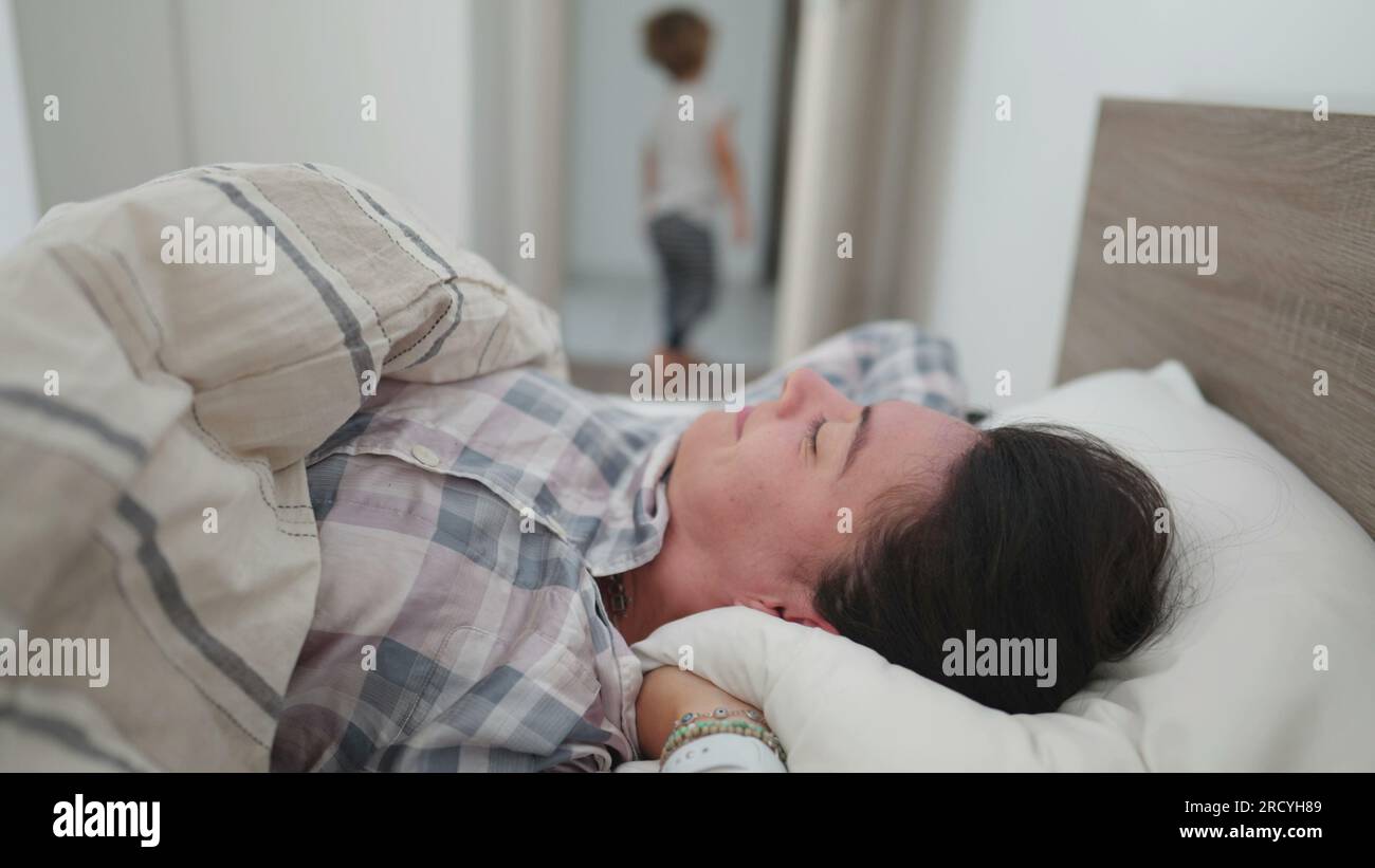 Woman getting up from bed rubbing face and starting the day Stock Photo