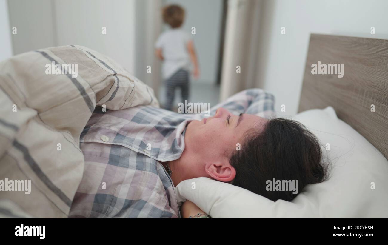 Woman getting up from bed rubbing face and starting the day Stock Photo