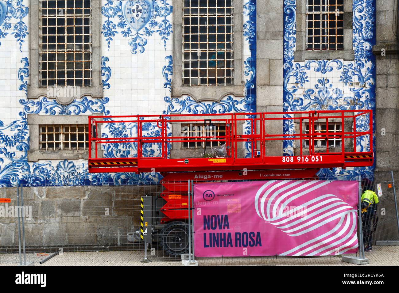 Scissor lift elevated platform parked next to azulejo tile covered side wall of Igreja do Carmo church, Porto / Oporto, Portugal Stock Photo