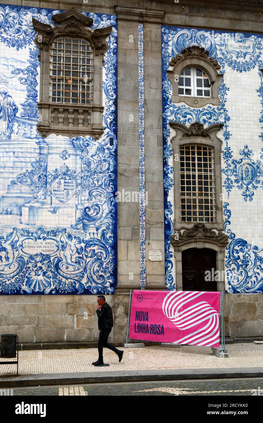 Man smoking a cigarette walking past azulejos / ceramic tiles on side of Igreja do Carmo church, Porto / Oporto, Portugal Stock Photo