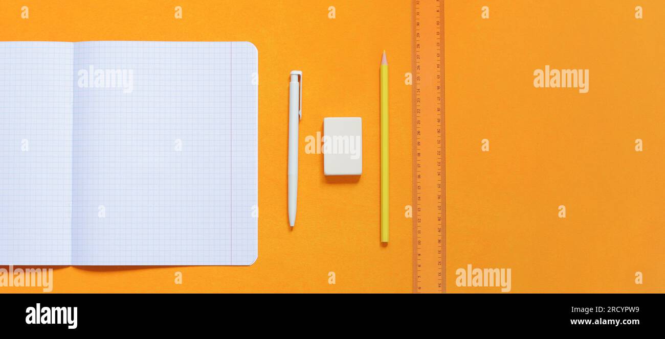 An open notepad with blank white sheets, a white pen, a pencil, a ruler ...