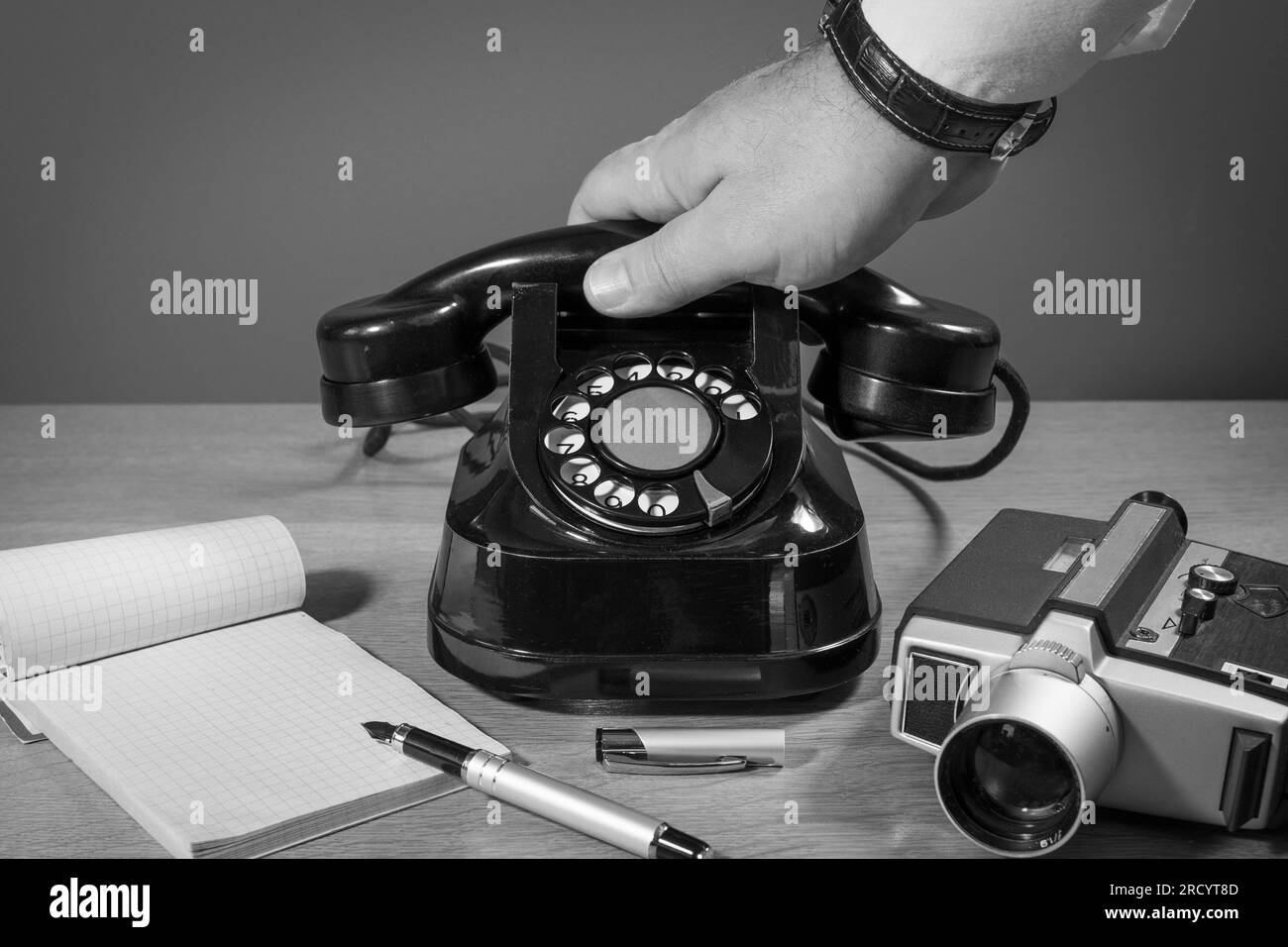 Exclusive reportage. Communications of the past. The hand reaches for the phone. Old telephone set on a wooden table, retro installation. Copy space Stock Photo
