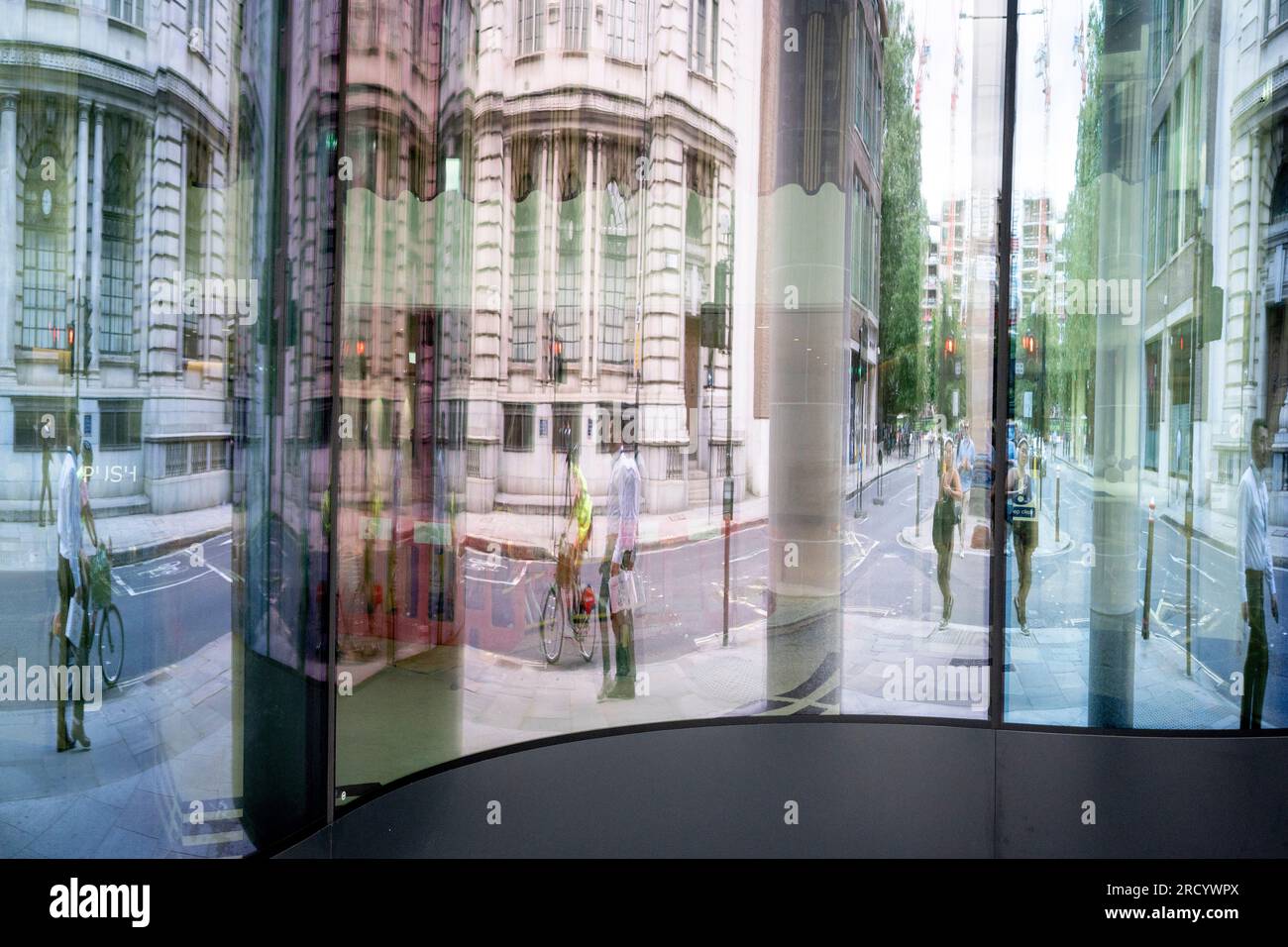 City workers are reflected and distorted in the glass entrance of an ...
