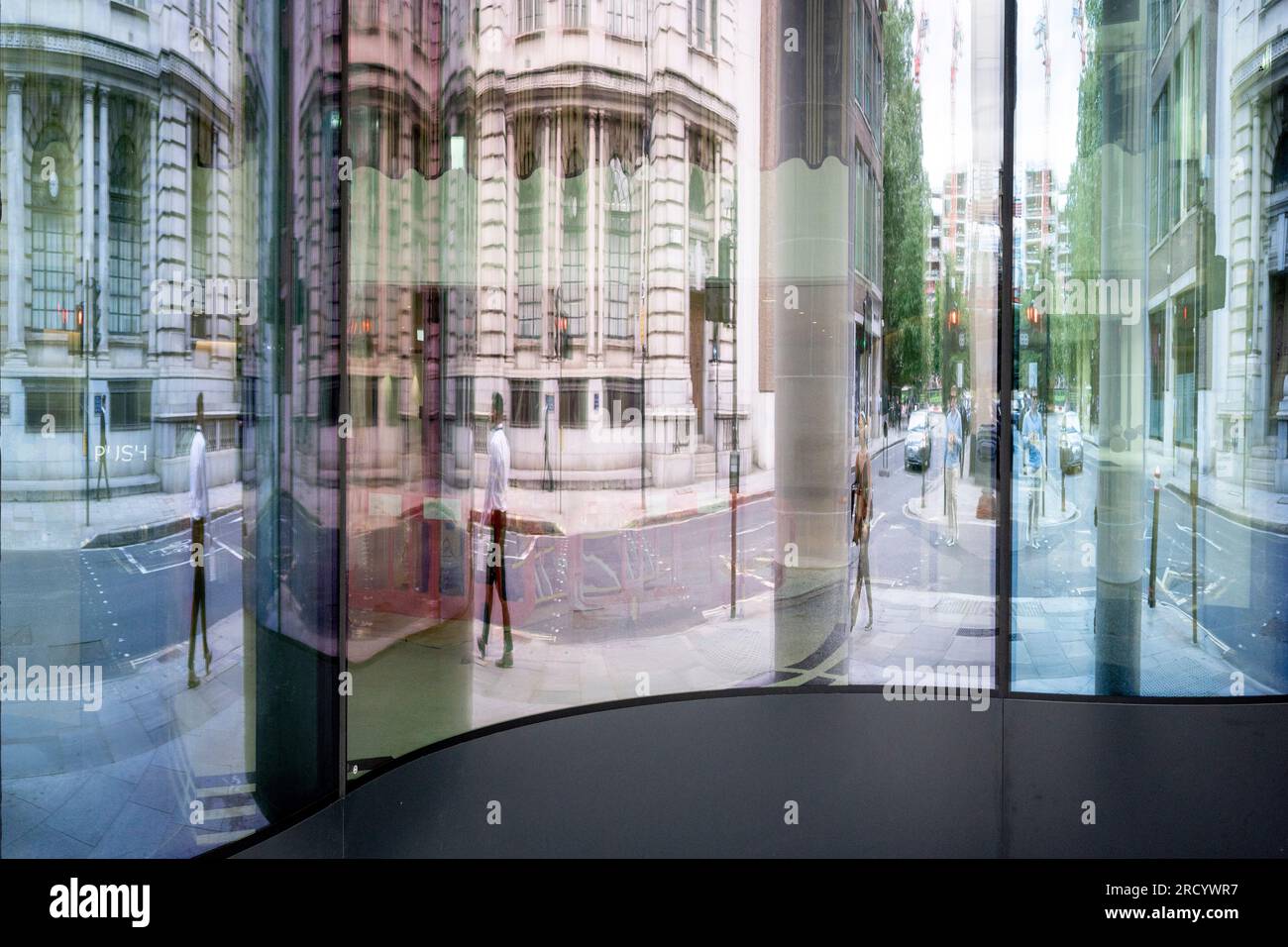 City workers are reflected and distorted in the glass entrance of an office workplace in the City of London, the capital's financial district, on 17th July 2023, in London, England. Stock Photo