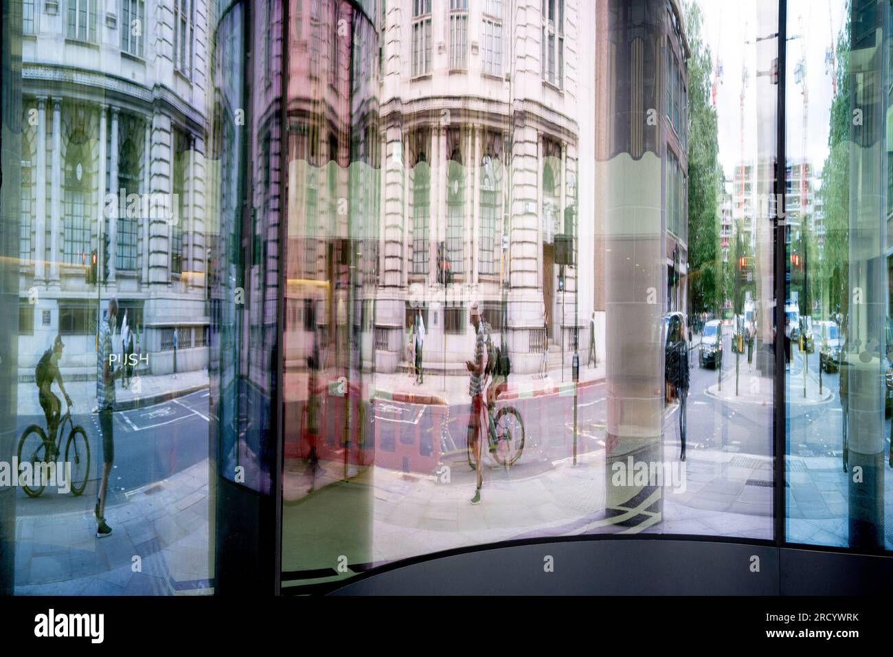 City workers and cyclists are reflected and distorted in the glass ...