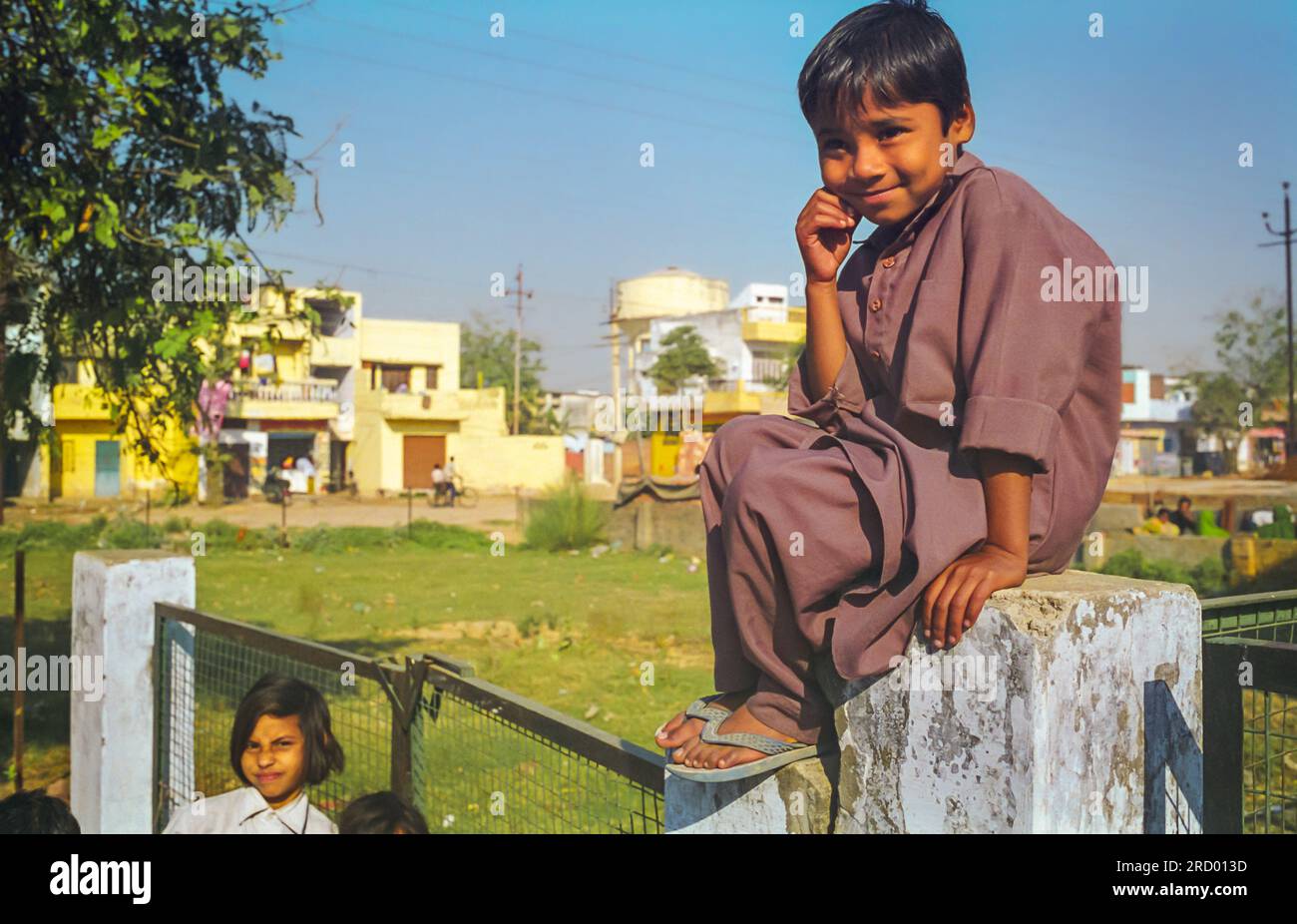 Agra, India, February 1999 Indian local boy sitting on a fence smiles