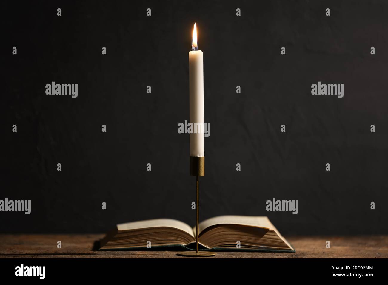 Beautiful burning candle and book on black background Stock Photo - Alamy