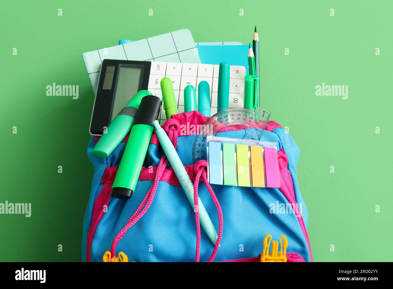 School backpack with different stationery on green background Stock Photo