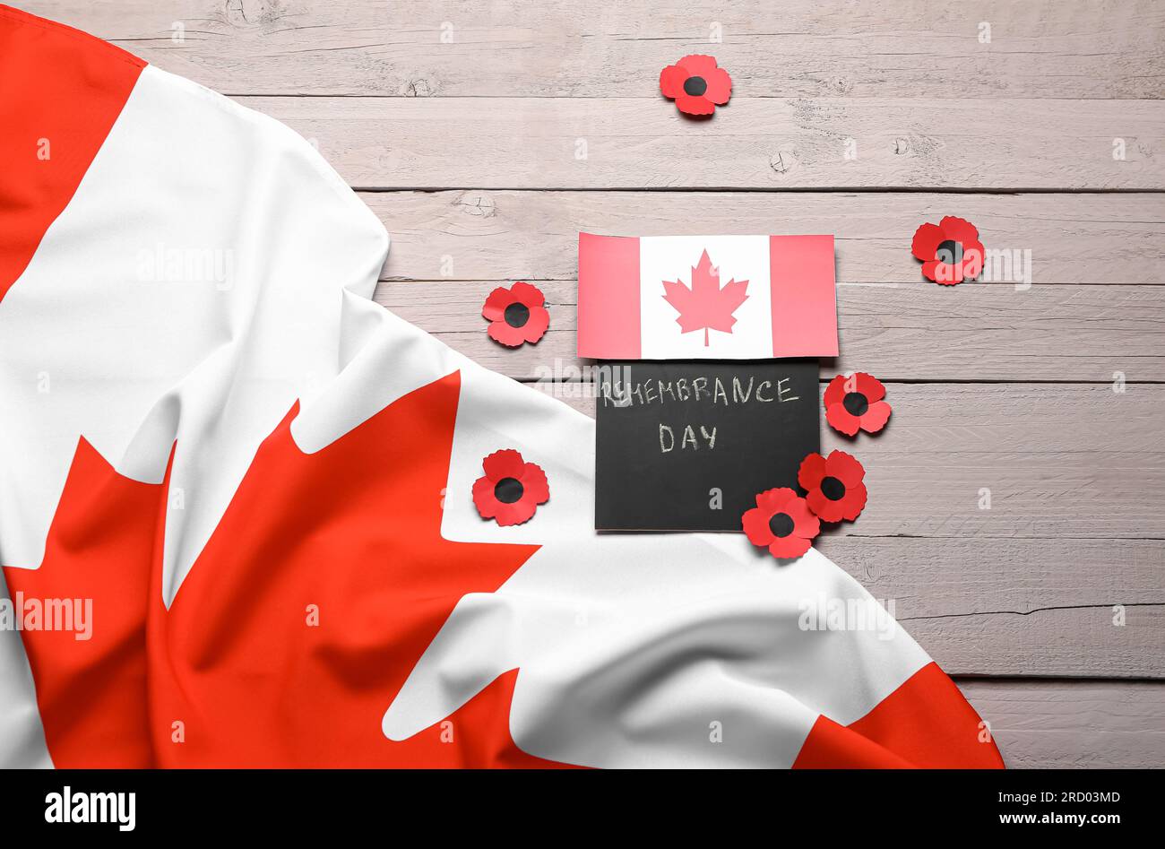 Poppy flowers with flags of Canada and card on wooden background