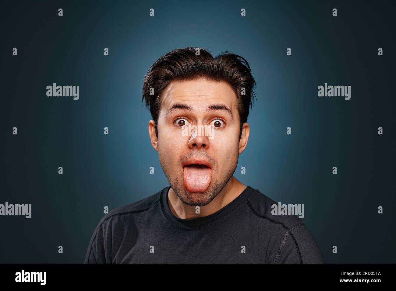 Young brunette man showing tongue emotional portrait Stock Photo