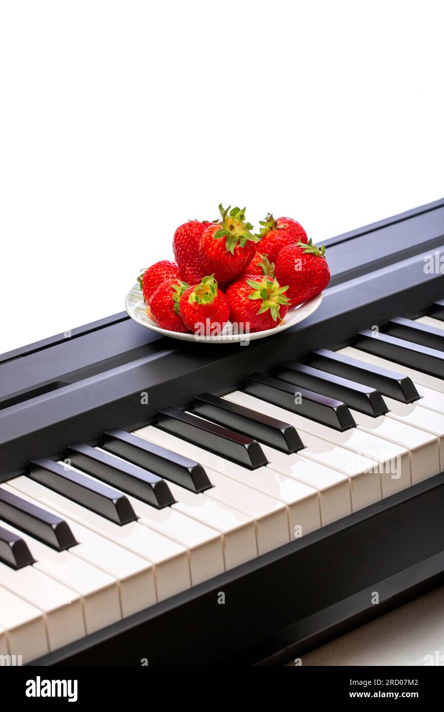 Three ripe strawberries on the piano keys Stock Photo Alamy