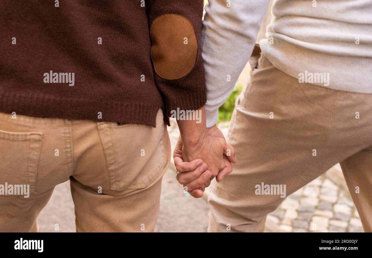 Closeup Of Hands Hold While Senior Couple Walking Outdoors Stock Photo