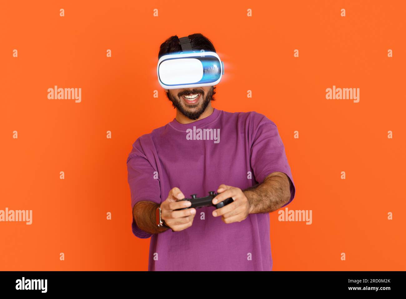 Smiling eastern young guy using VR glasses and joystick Stock Photo