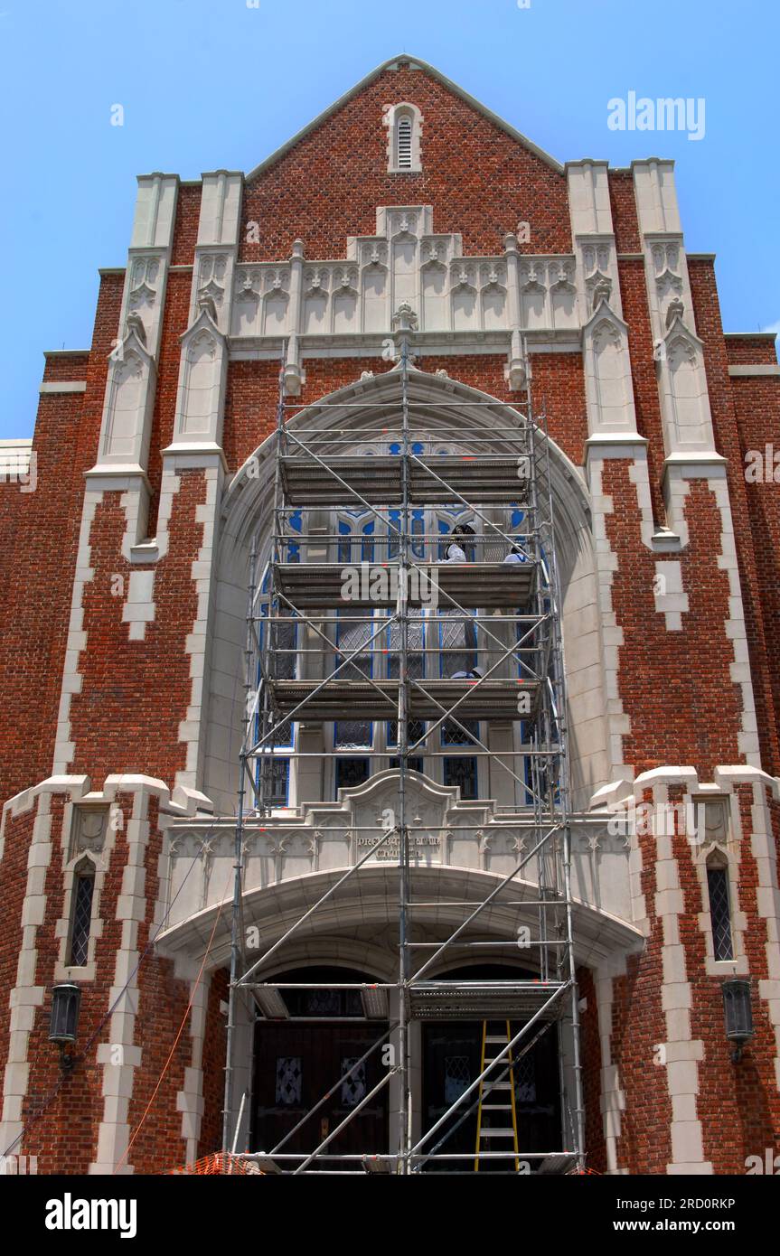 Workers stand on scaffolding to repaint fixtures around stained glass