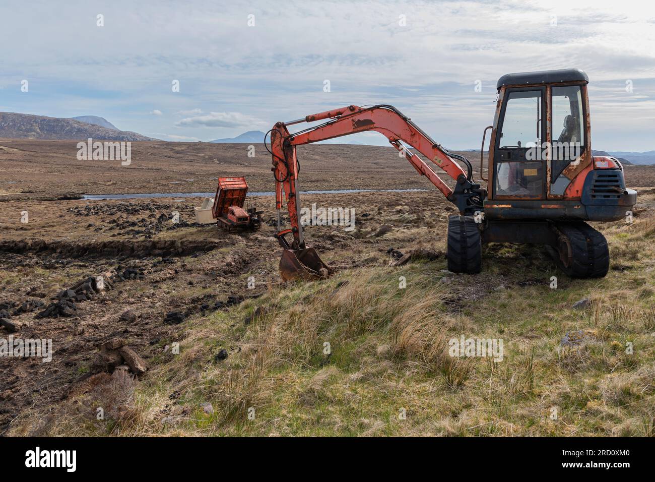 Digging for peat in a glen in Scotland using a mechanical digger and