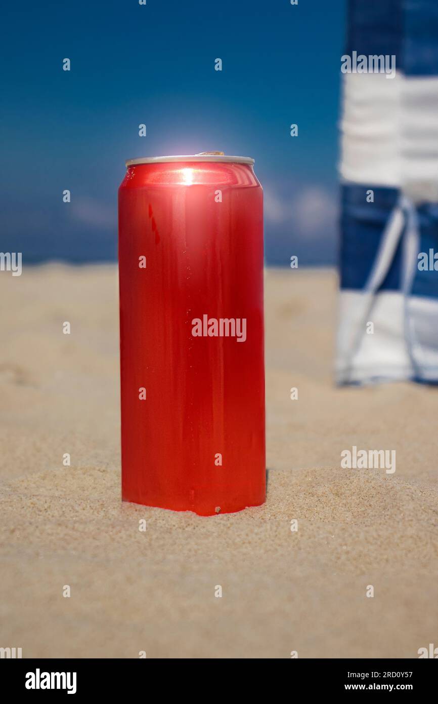 Red 330 ml can of soda. A can stand on the sand, on the beach, against