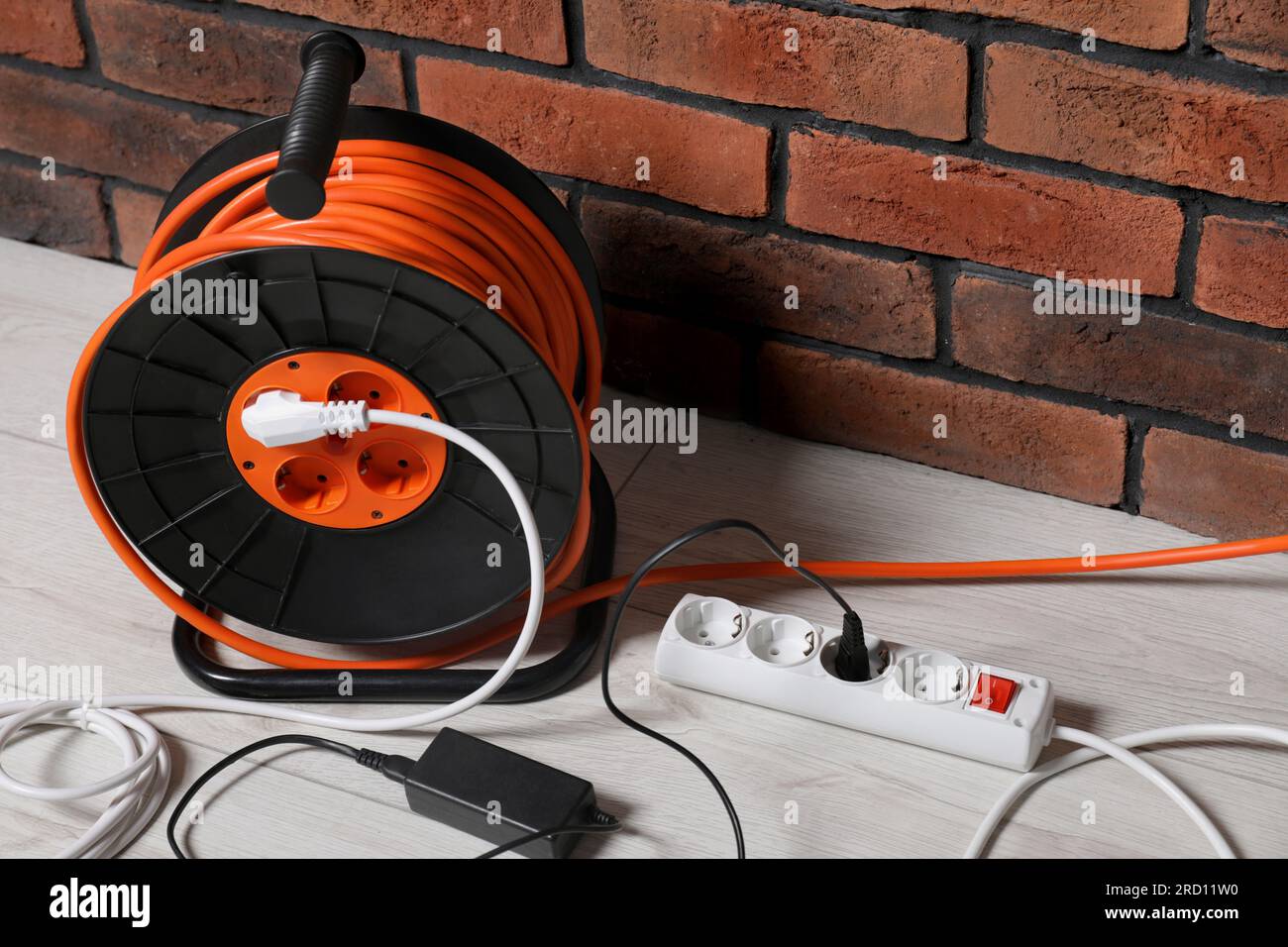 Extension cord reel on white floor near brick wall. Electrician's equipment  Stock Photo - Alamy
