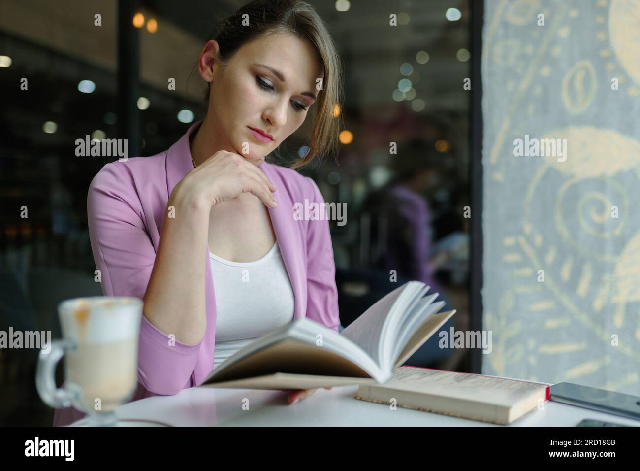 Young caucasian woman reading a book in a coffee shop Stock Photo