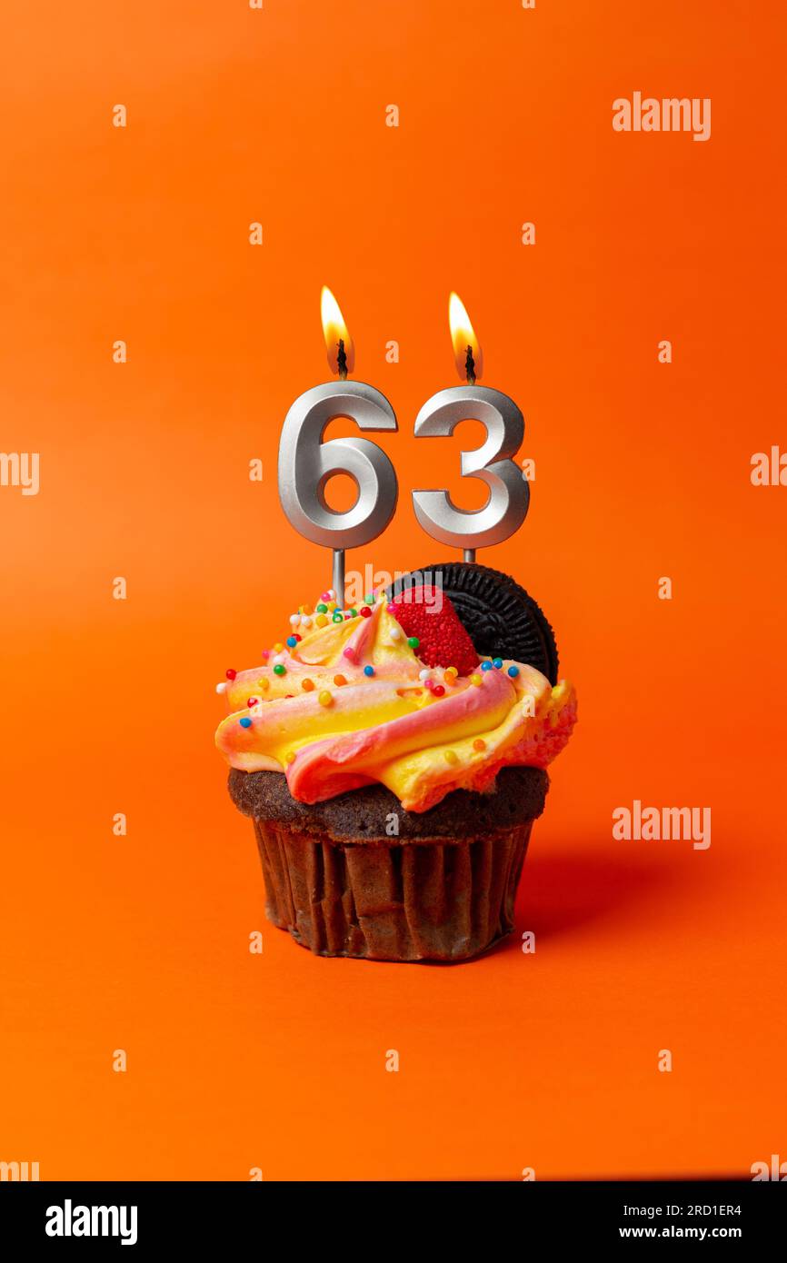 birthday cake with number 63 - cupcake on orange background with birthday candles Stock Photo