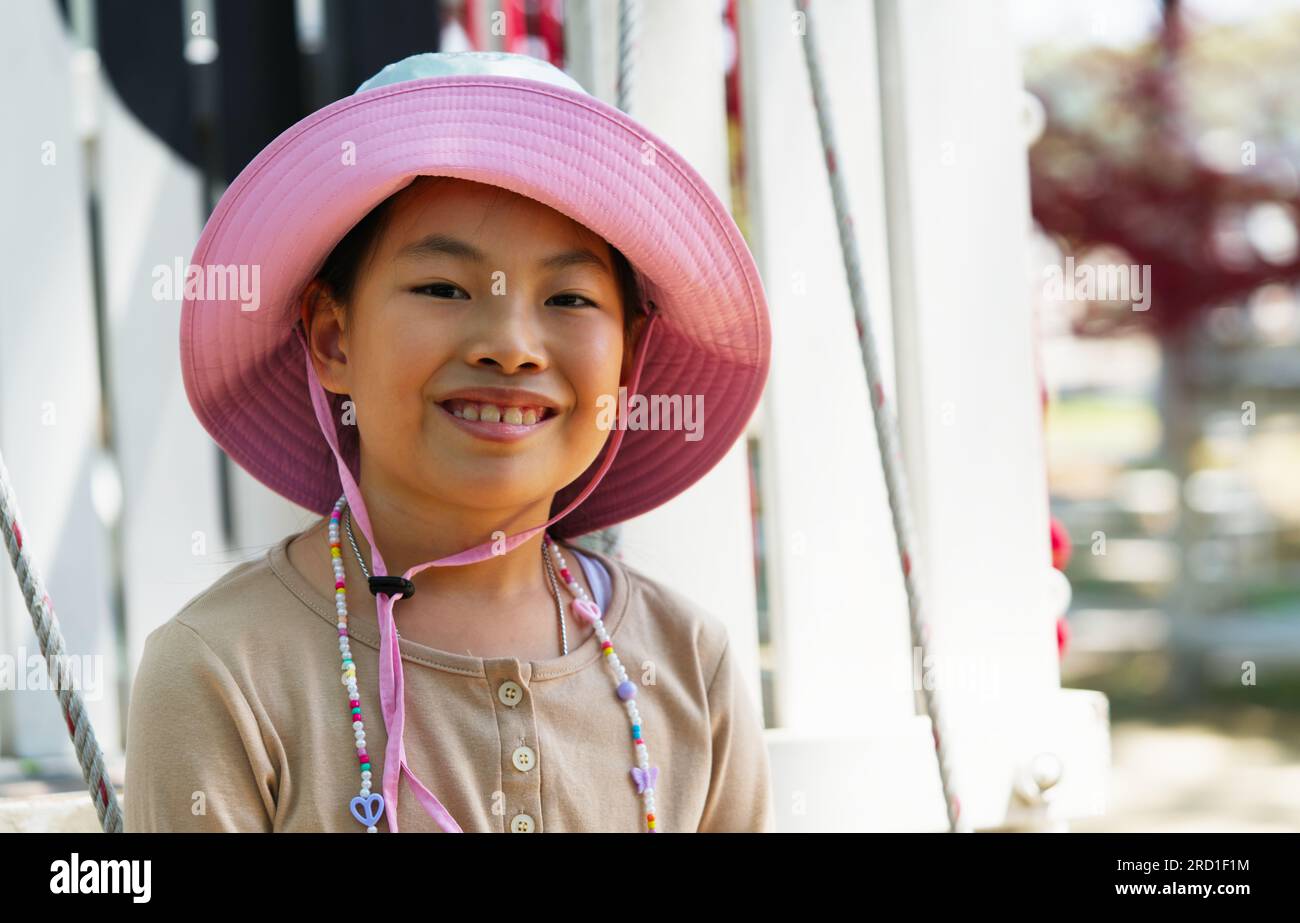 Portrait Asian child girl on vacation, child girl at 8 or 9 years old, outdoor photography, wearing UV protection hat, smiling, looking at camera, emp Stock Photo