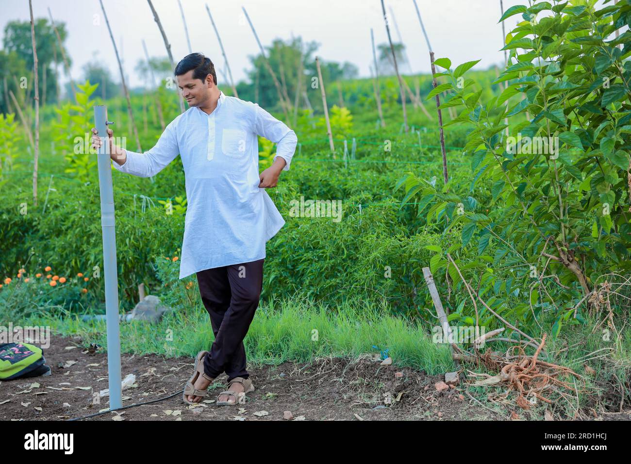 Happy Indian farmer, holding pipe in hand and looking camera Stock Photo