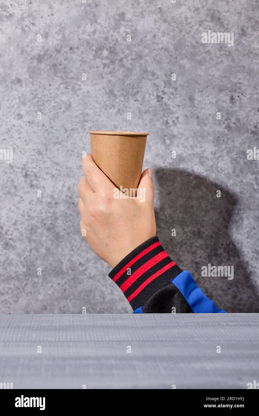 take away coffee cup in human hand on grey background, selective focus Stock Photo