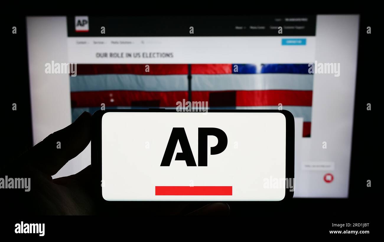Person holding smartphone with logo of US news agency Associated Press (AP) on screen in front of website. Focus on phone display. Stock Photo