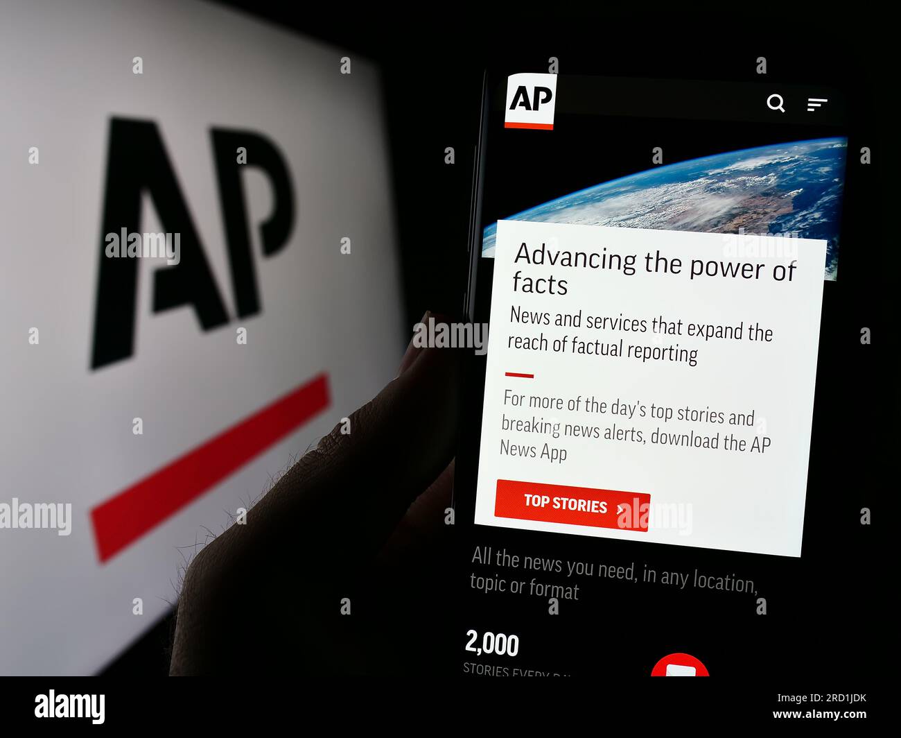 Person holding cellphone with web page of US news agency Associated Press (AP) on screen in front of logo. Focus on center of phone display. Stock Photo