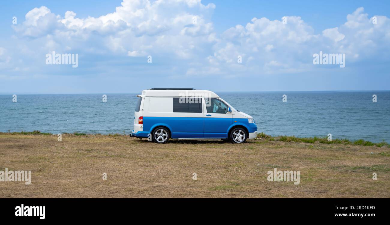 Blue vintage camper van parked on a grassy plain with the Atlantic ...