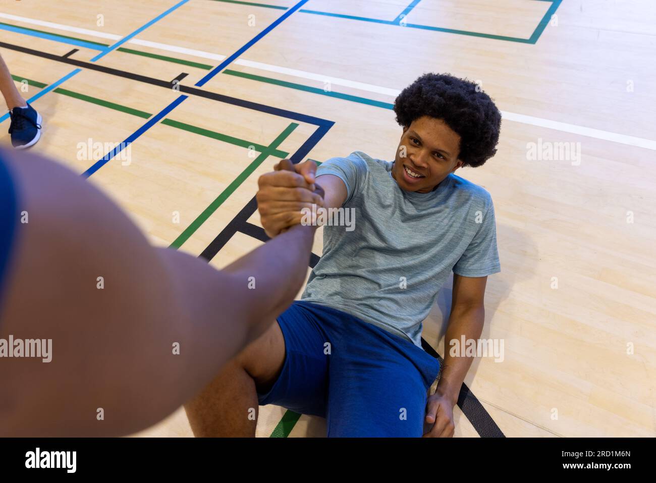 Diverse male basketball players helping to get up at gym Stock Photo Alamy