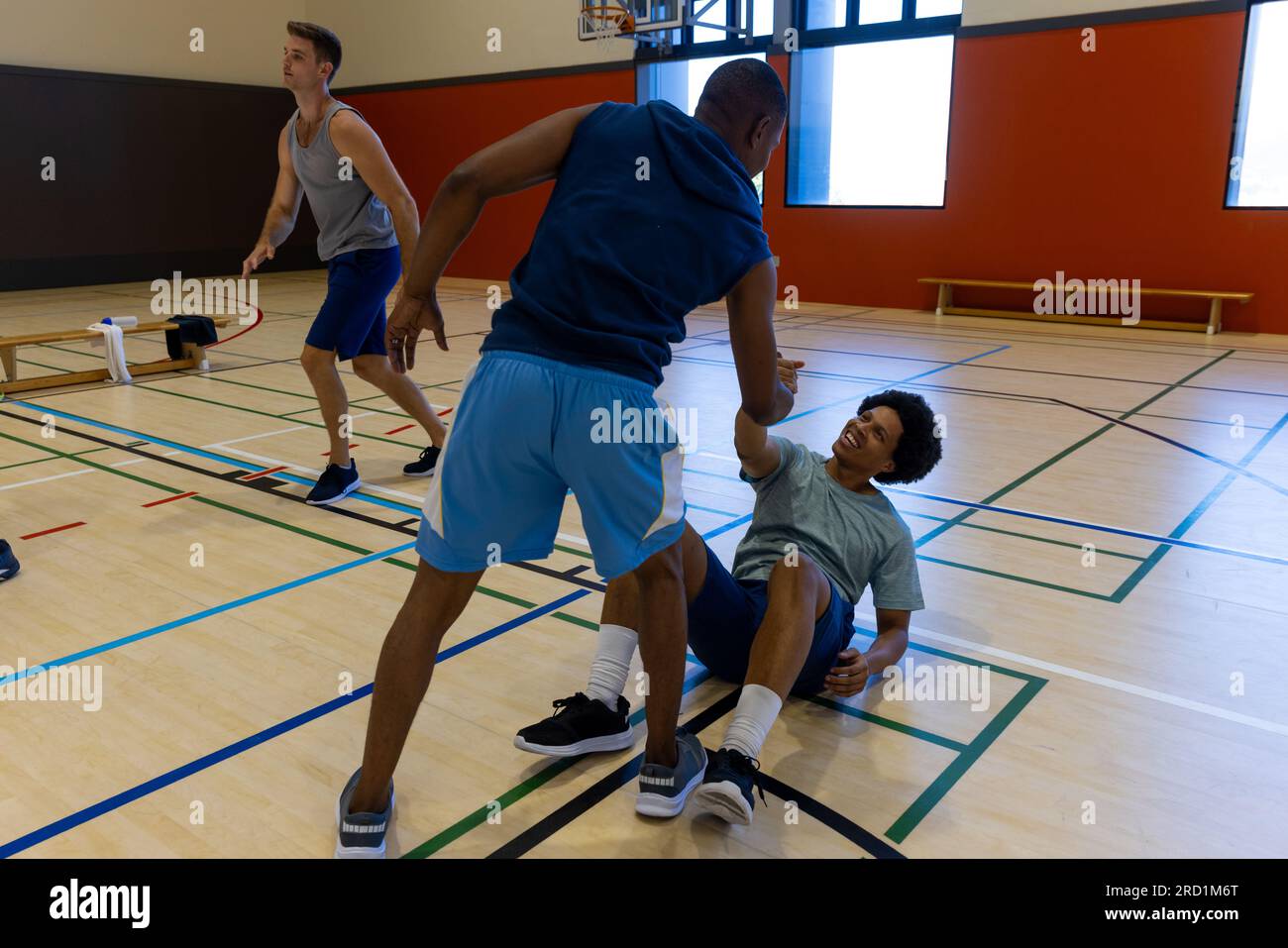 Diverse male basketball players helping to get up at gym Stock Photo Alamy