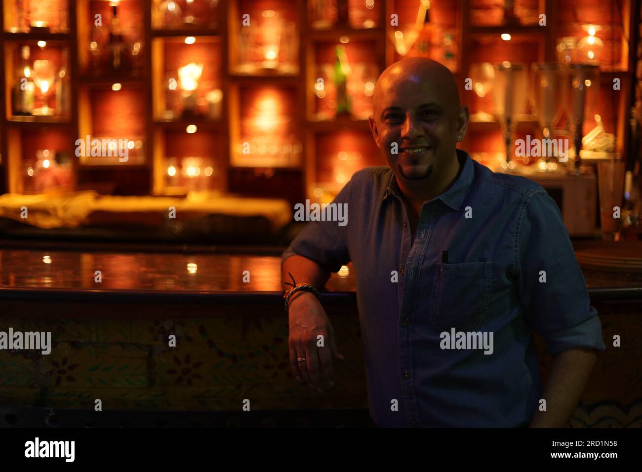 Young and flamboyant handsome bald guy standing on bar counter