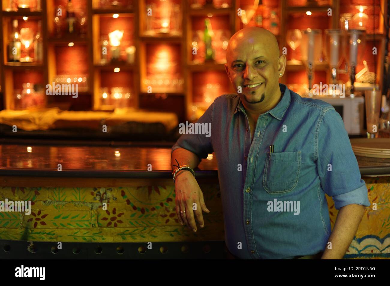 Young and flamboyant handsome bald guy standing on bar counter