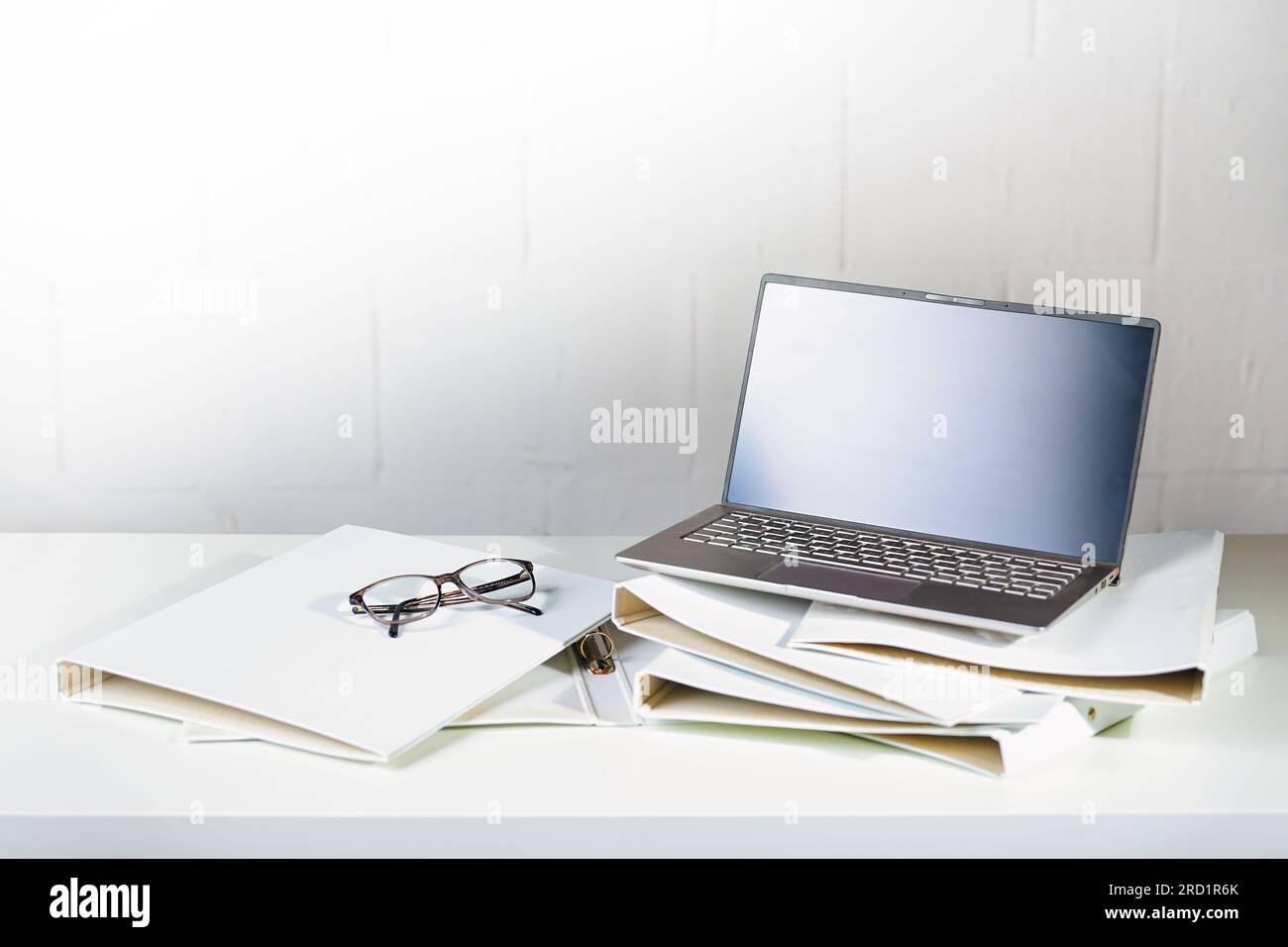 Laptop and glasses on several white ring binders on an office desk, administration and business work concept, copy space, selected focus, narrow depth Stock Photo