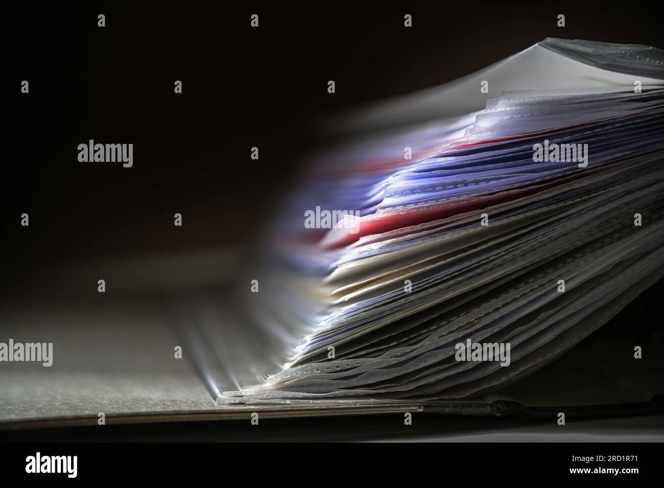 Close up of documents in transparent sleeves or punched pockets in a ring binder against a dark background, concept for office and business, copy spac Stock Photo