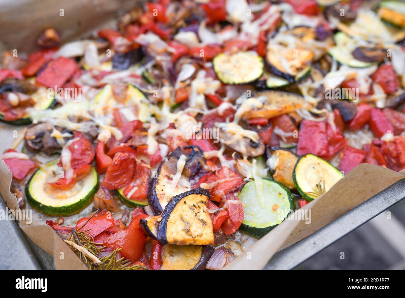 Oven-baked vegetables with eggplant, zucchini, bell pepper, onions and parmesan cheese on a baking tray, copy space, selected focus, narrow depth of f Stock Photo