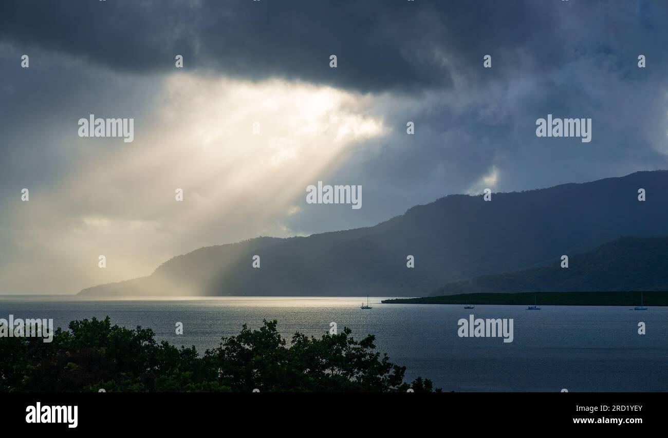 Sunlight breaking through stormy clouds onto the sunlit ocean. Stock Photo