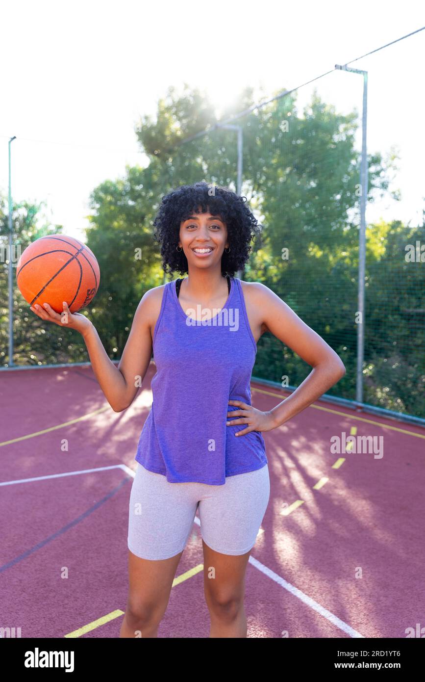 Portrait of happy biracial female basketball player wearing holding