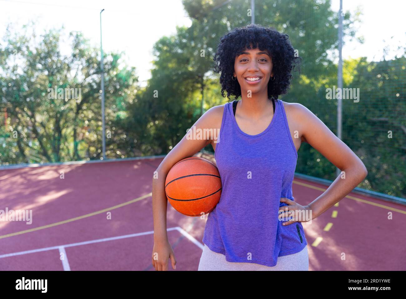 Portrait of happy biracial female basketball player wearing holding